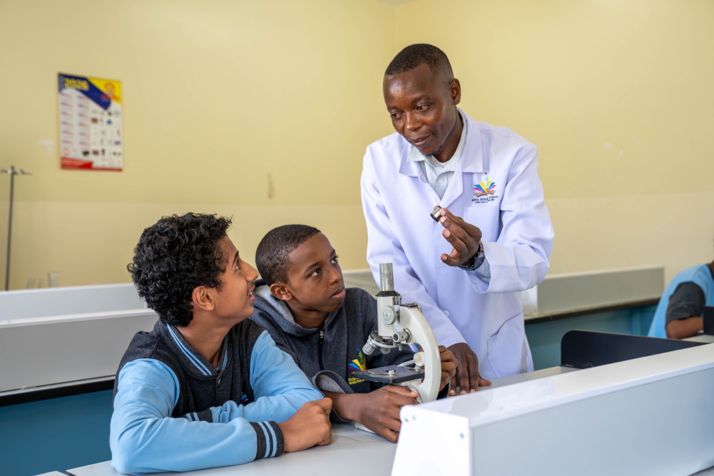 A teacher showing pupils a microscope in the science lab at Huda Integrated School