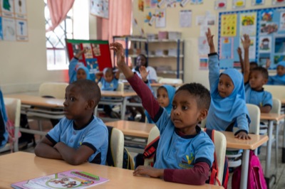 Primary pupils raising their hands in class at Huda Integrated School
