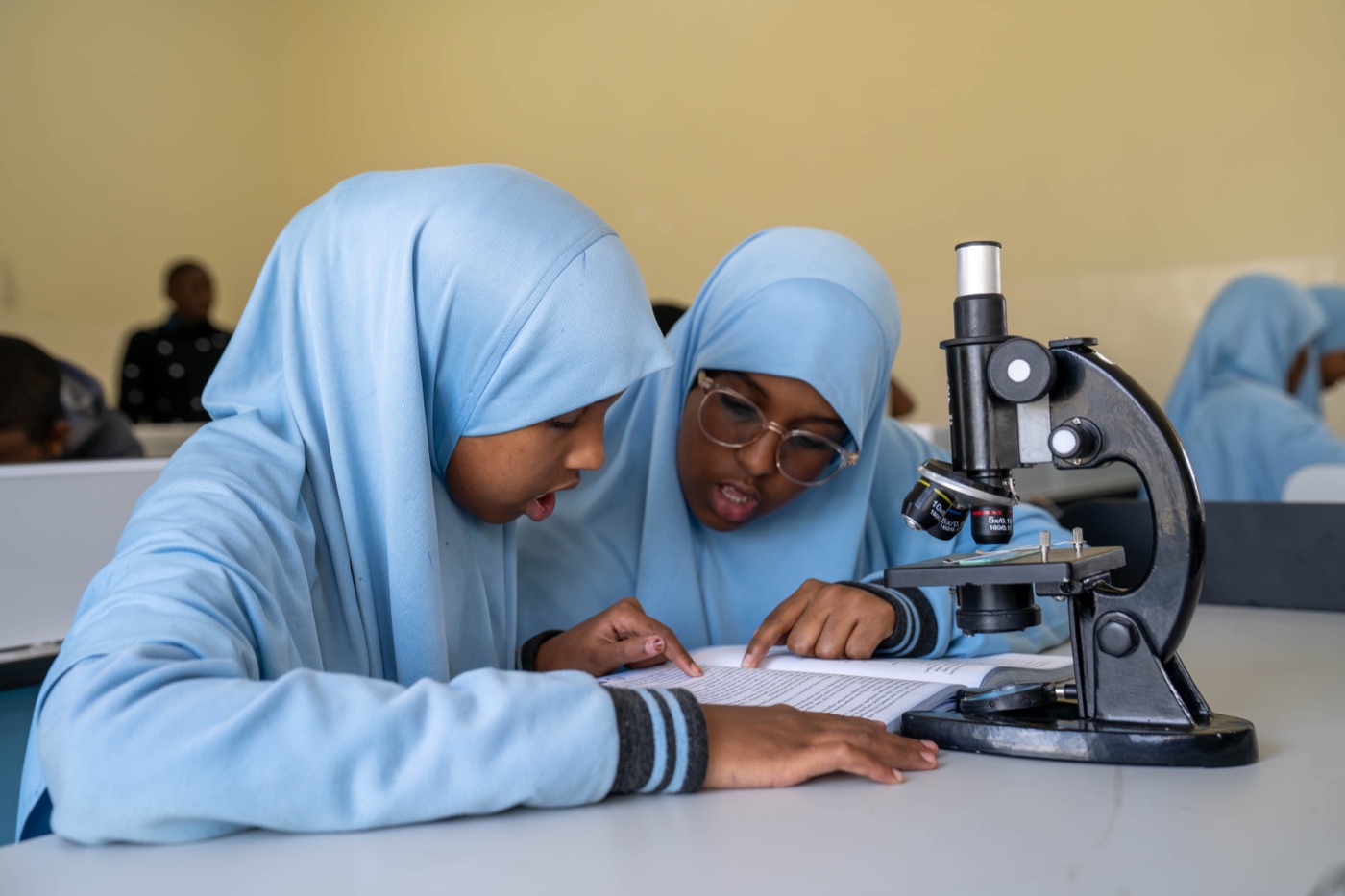 Pupils using a microscope together in the science lab at Huda Integrated School